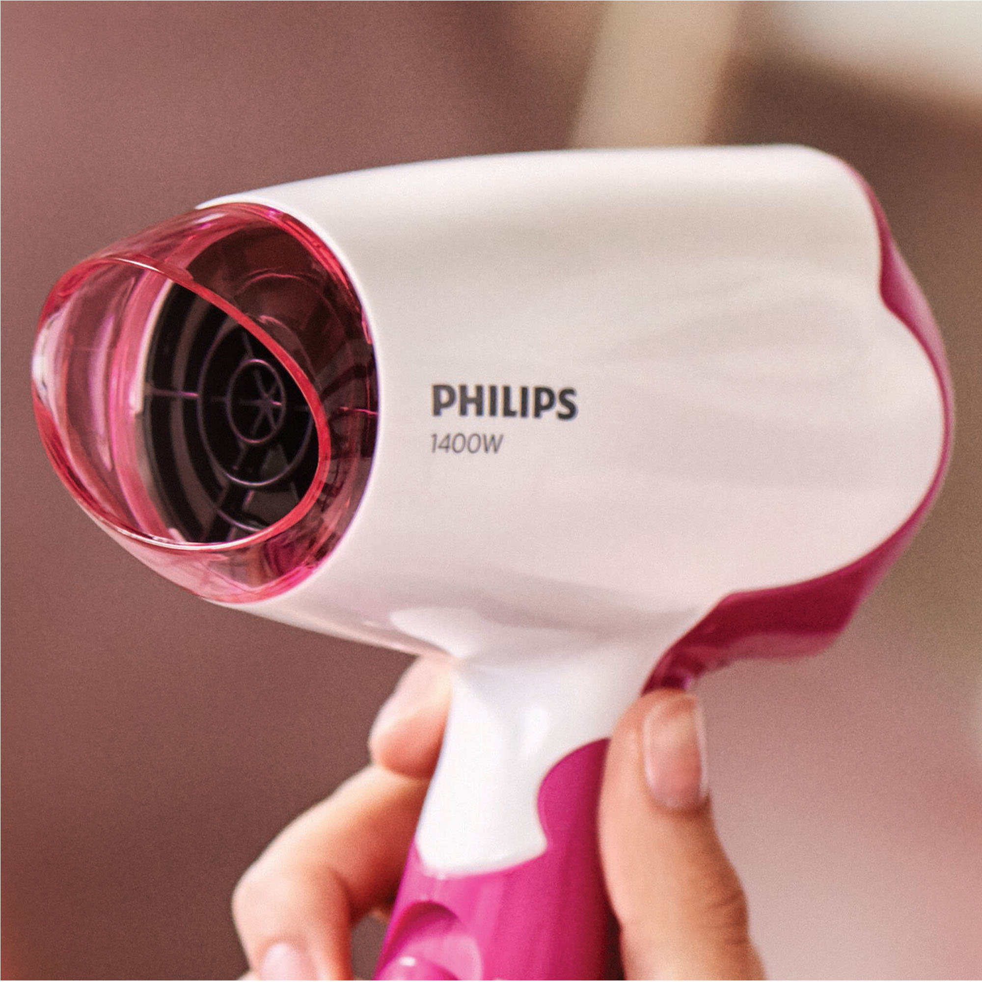 Trzymana jest biało-różowa suszarka do włosów.