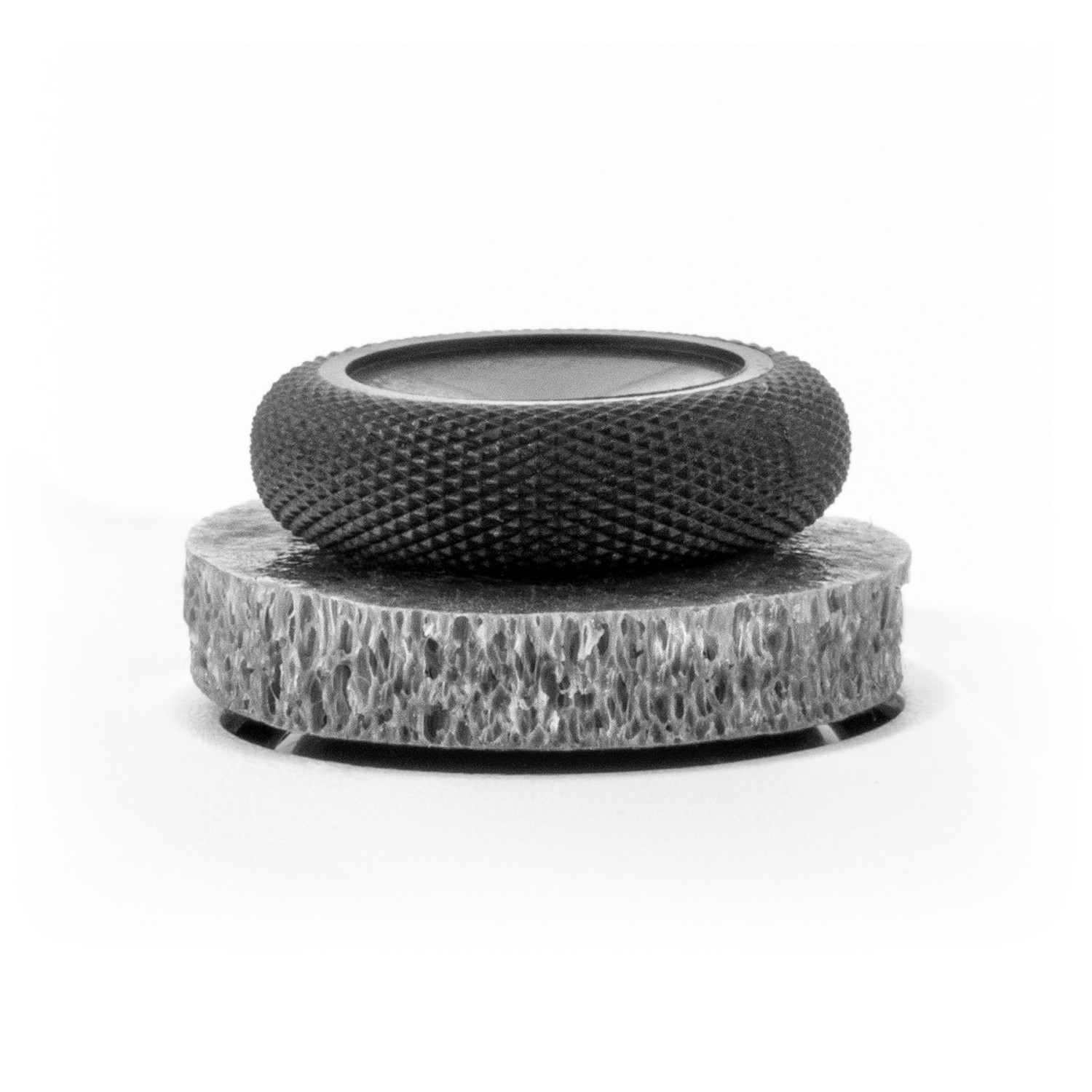A black and gray decorative item with a textured top and a textured base.