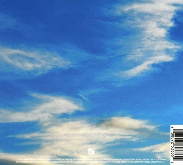 Ein strahlend blauer Himmel mit weißen Wolken füllt das Bild. Der untere Bildrand zeigt Text.