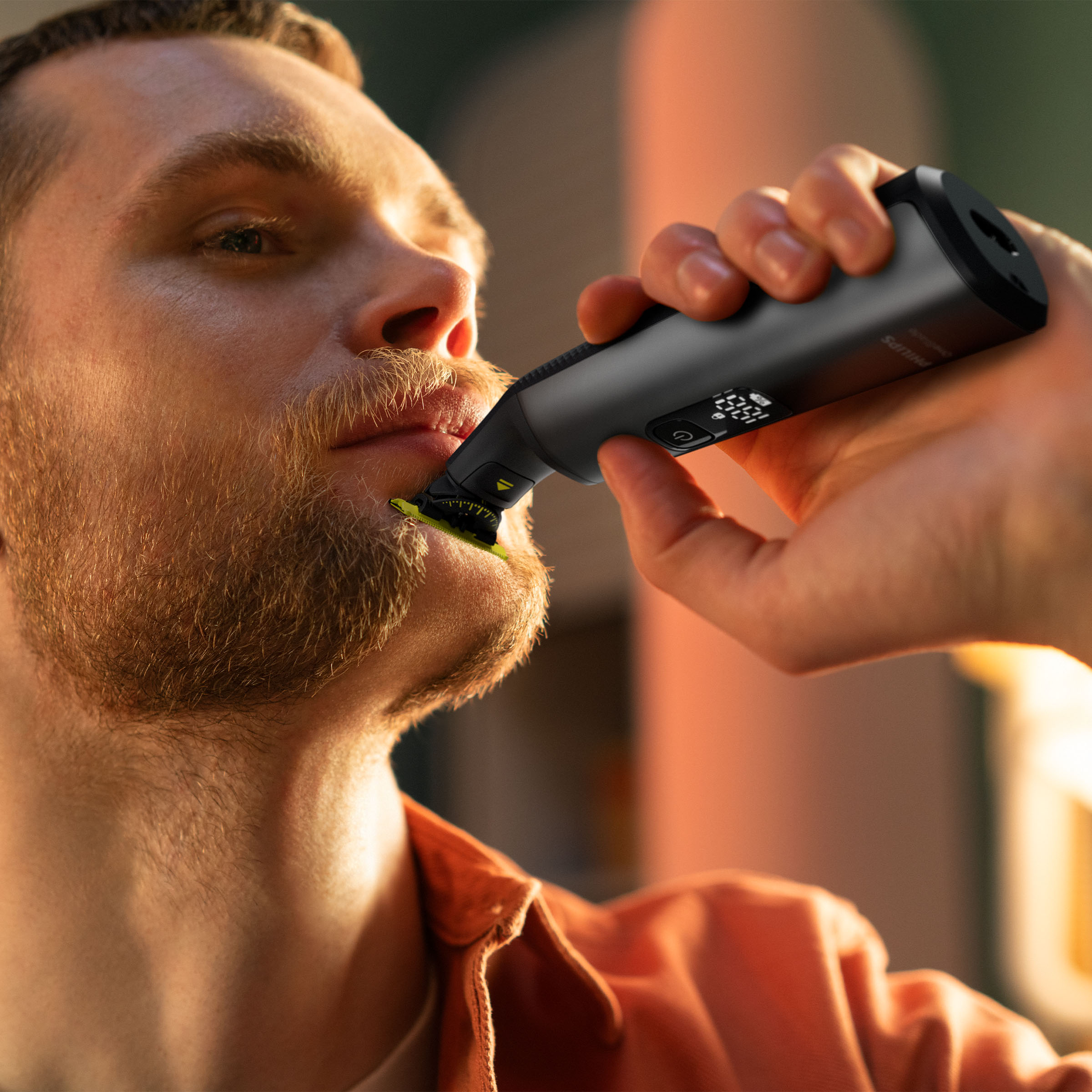 Mężczyzna goli brodę czarną golarką elektryczną. Zbliżenie na twarz.