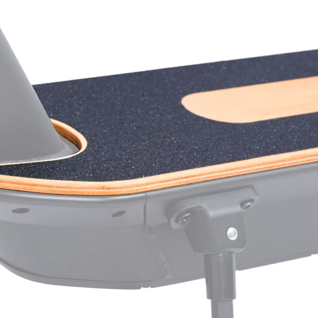 Zbliżenie na pokład hulajnogi, z czarną, teksturowaną powierzchnią i drewnianą krawędzią.