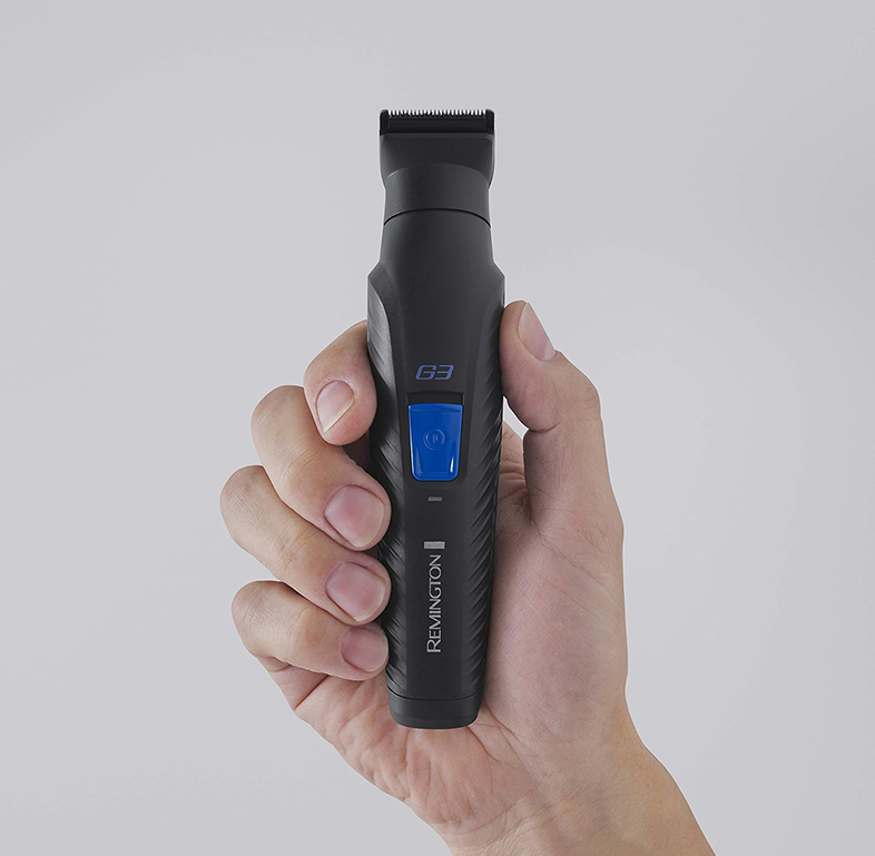 Férfi fekete Remington G3 trimmert tart, kék gombbal és Remington logóval. Szürke háttér.