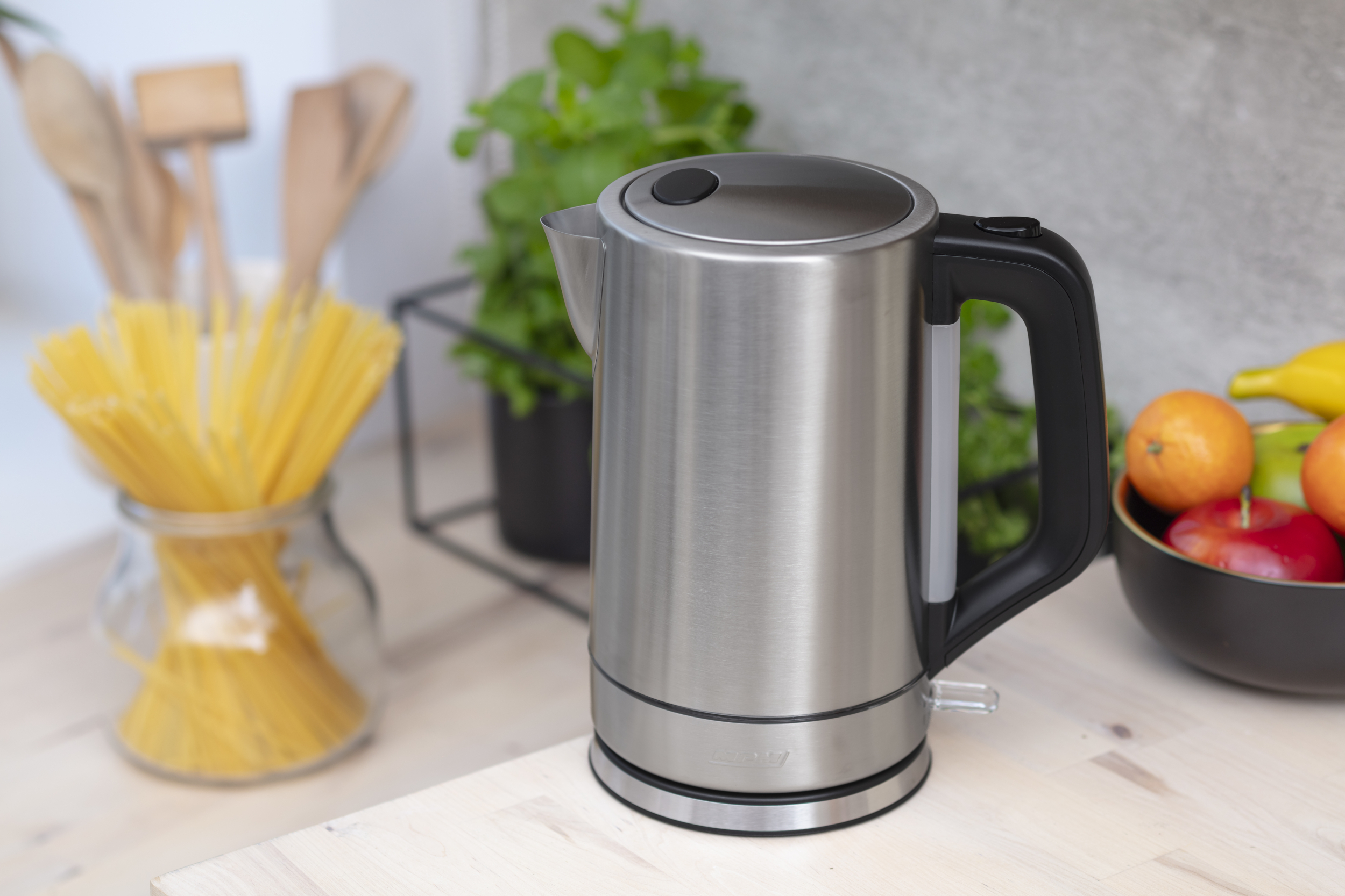 Czajnik elektryczny ze stali nierdzewnej na blacie kuchennym z produktami spożywczymi.