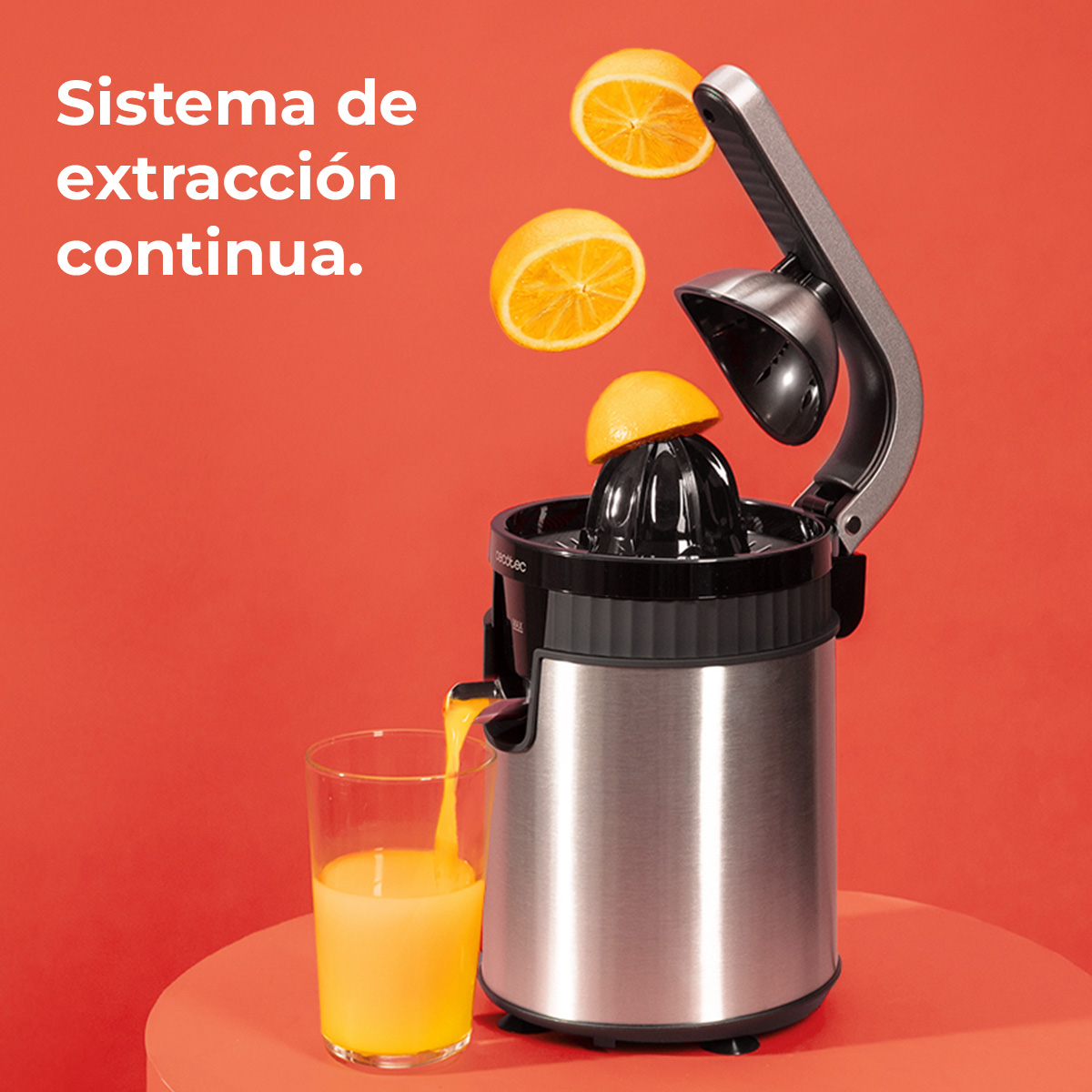 Exprimidor con naranjas y zumo. Se están exprimiendo naranjas en un vaso, fondo rojo.