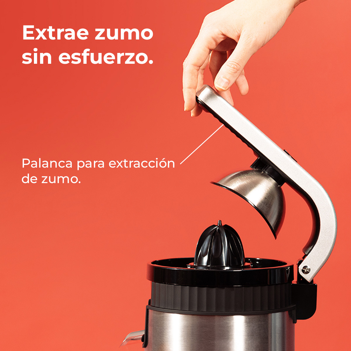Mano exprimiendo un exprimidor. El exprimidor es plateado y negro sobre un fondo rojo. Instrucciones en español.