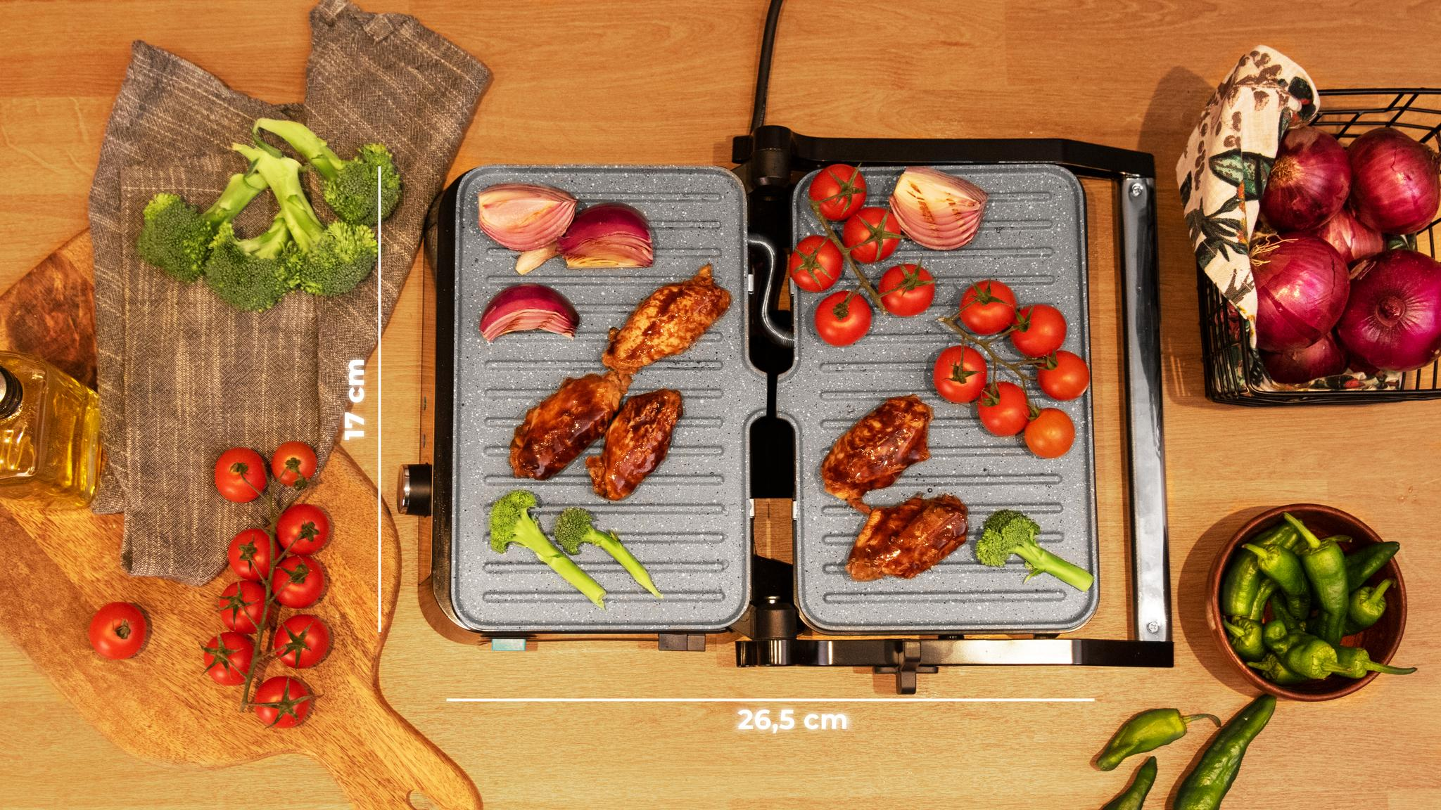 Parrilla con comida: tomates, cebollas, brócoli y alitas. Tabla de madera con tomates. Vista superior.