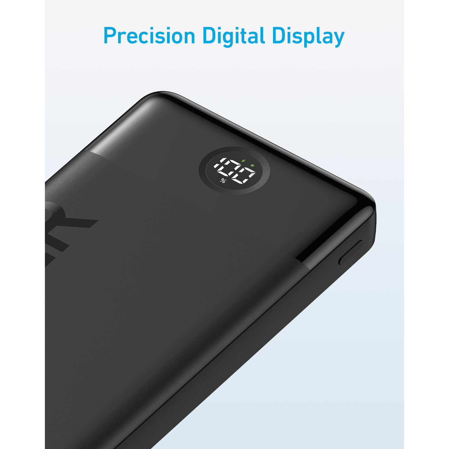 Close-up of a black portable power bank with a digital display showing 100% charge.