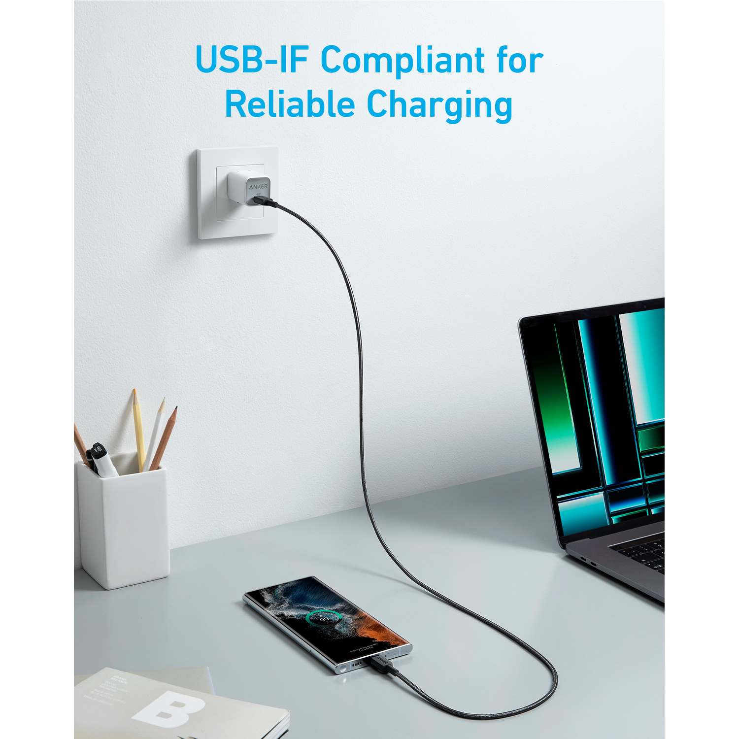 Anker charging cable plugged into a wall outlet, charging a phone and a laptop.