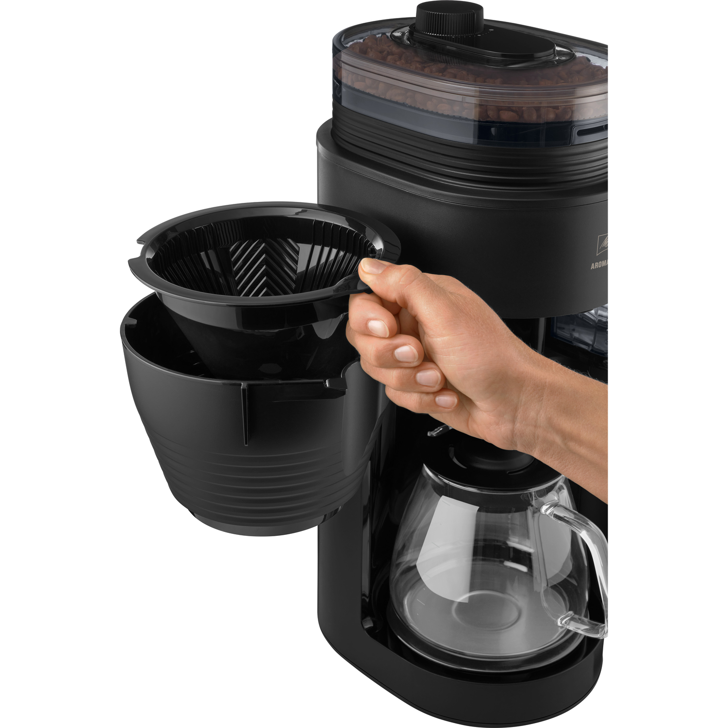 Zwarte koffiezetapparaat. Hand houdt het filter vast. Koffiebonen zichtbaar. Transparante glazen kan.