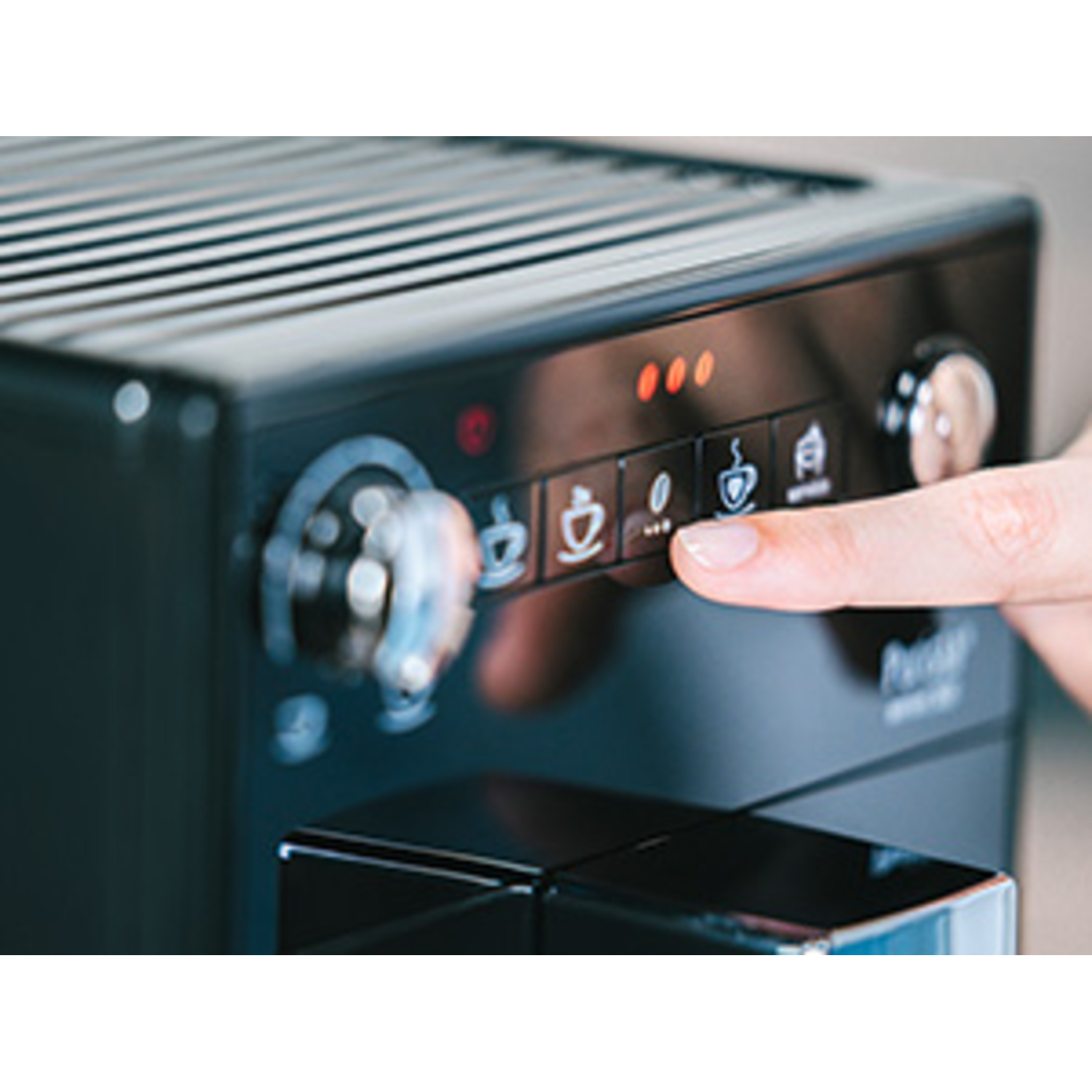 Een close-up van een bedieningspaneel van een koffiemachine met een vinger die op de espressoknop drukt.