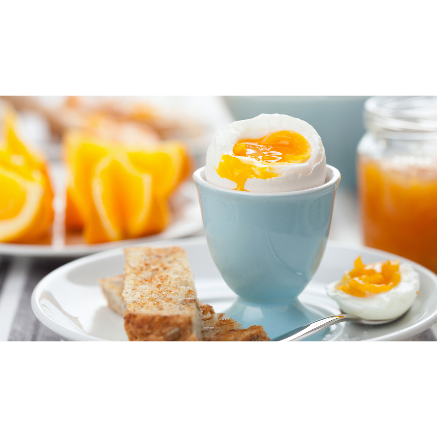 A soft-boiled egg in a blue egg cup, with toast and orange slices on a plate.