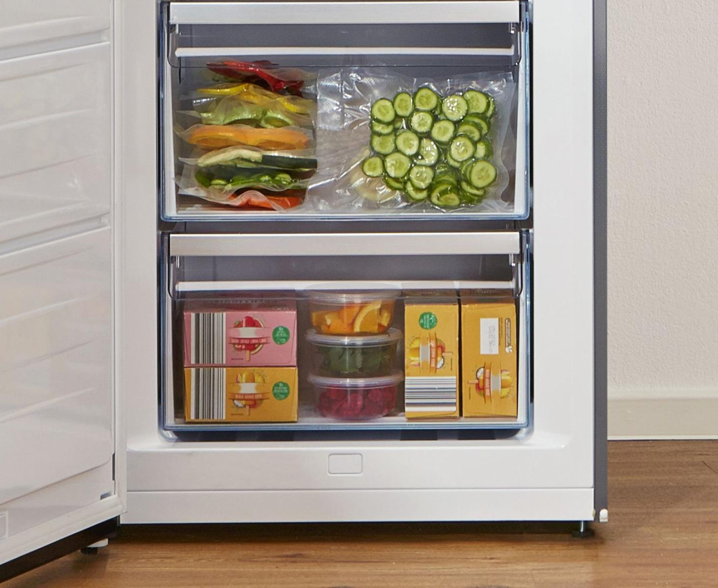 Wnętrze zamrażarki ze stosami zapakowanych warzyw i owoców. Białe wnętrze.