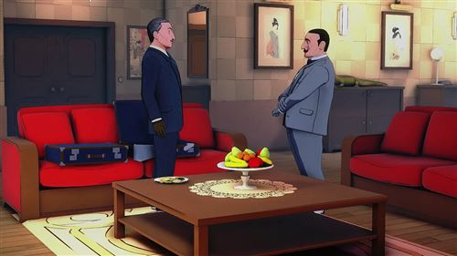 Dos hombres parados en una habitación con sofás rojos, hablando. Una mesa tiene fruta. Hay pinturas en la pared.