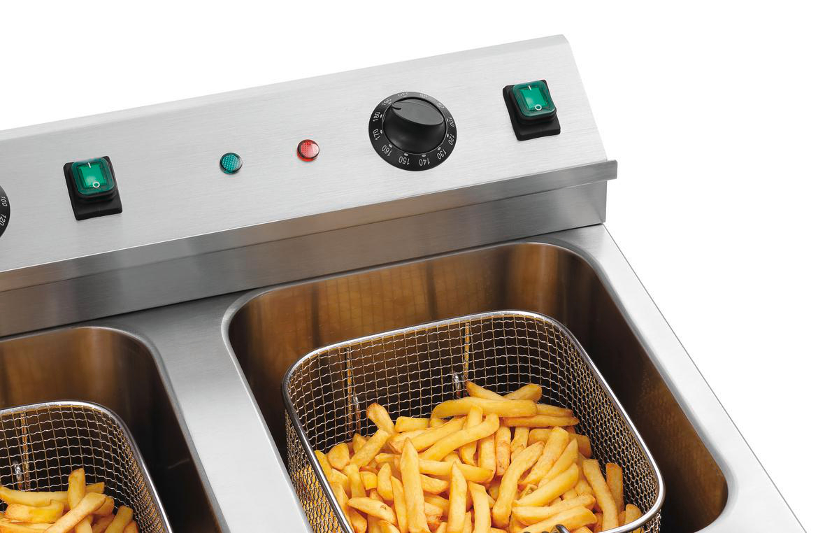 Eine Edelstahl-Fritteuse mit Pommes Frites in einem Korb. Sie hat Schalter, einen Temperaturregler und Lichter.