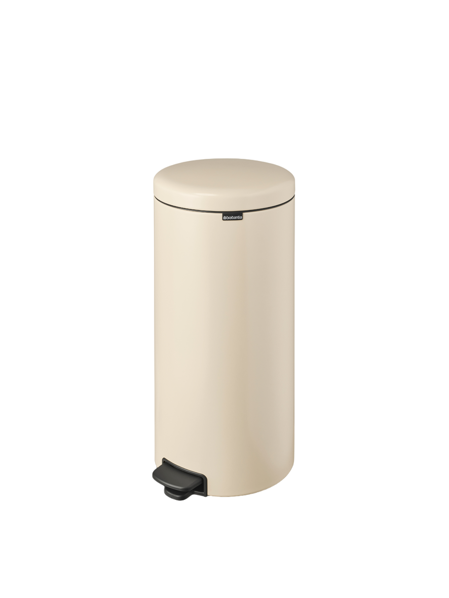 Cremefarbener Brabantia Treteimer mit schwarzem Pedal und schwarzem Deckelbesatz. Schwarzer Hintergrund.