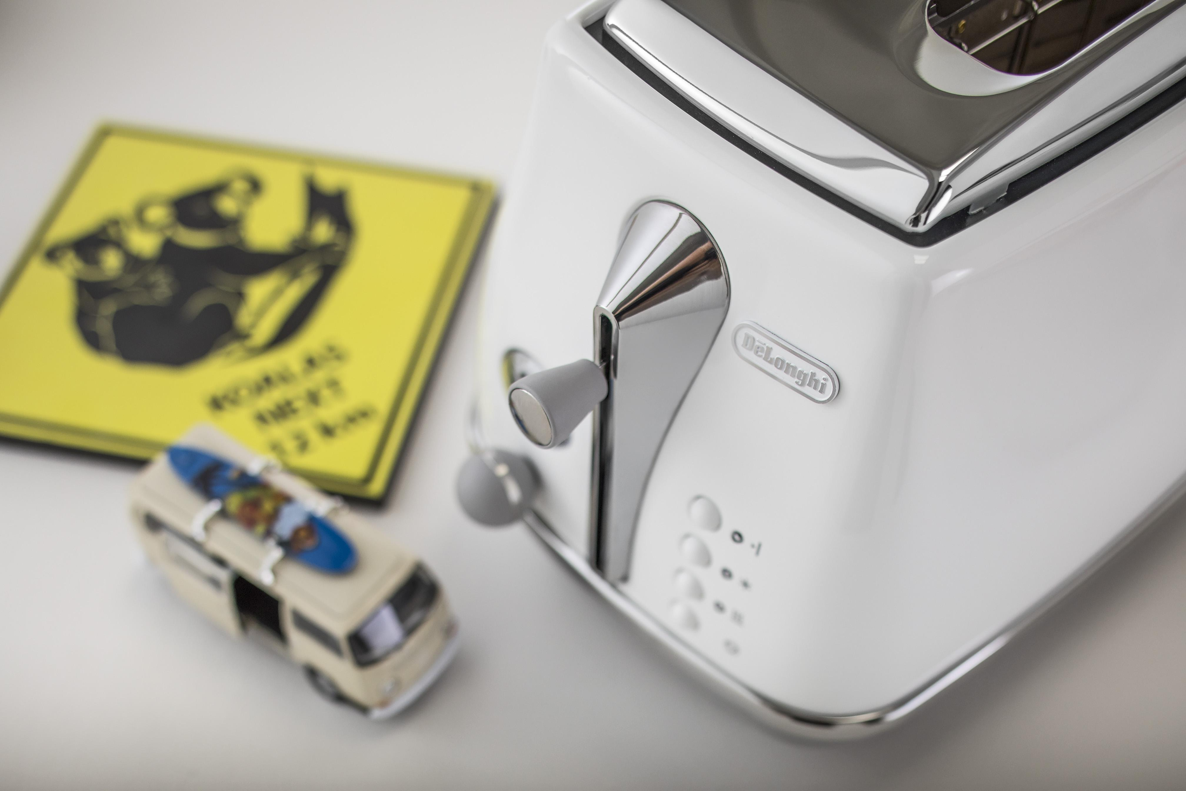 Biały toster z zabawką deski surfingowej i znakiem z koalami.