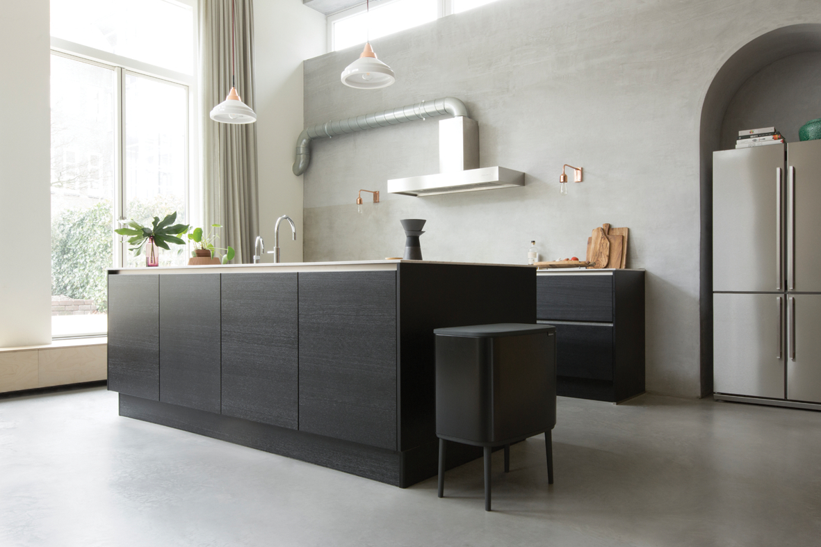 Eine moderne Küche mit dunklen Holzschränken, einem Kühlschrank aus Edelstahl und einem Mülleimer.