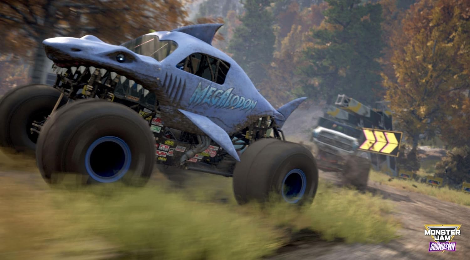 Un monster truck con diseño de tiburón compitiendo en una pista de tierra. Otro camión al fondo.