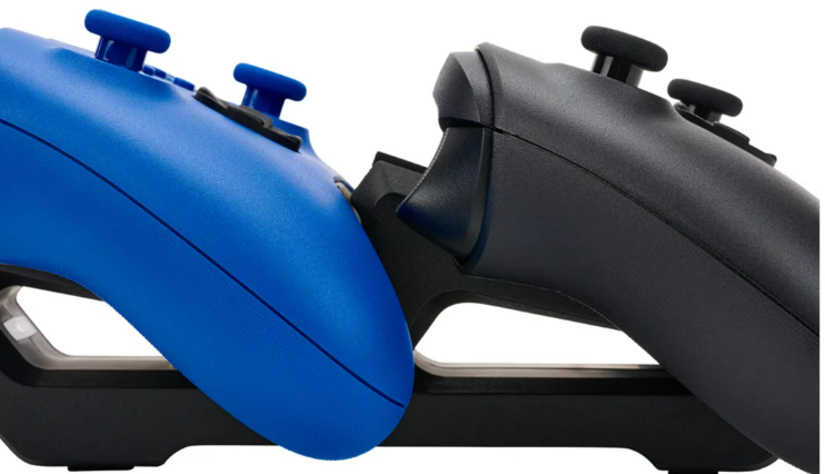 Zwei Gamecontroller auf einer Ladestation. Einer ist blau, einer ist schwarz. Weißer Hintergrund.
