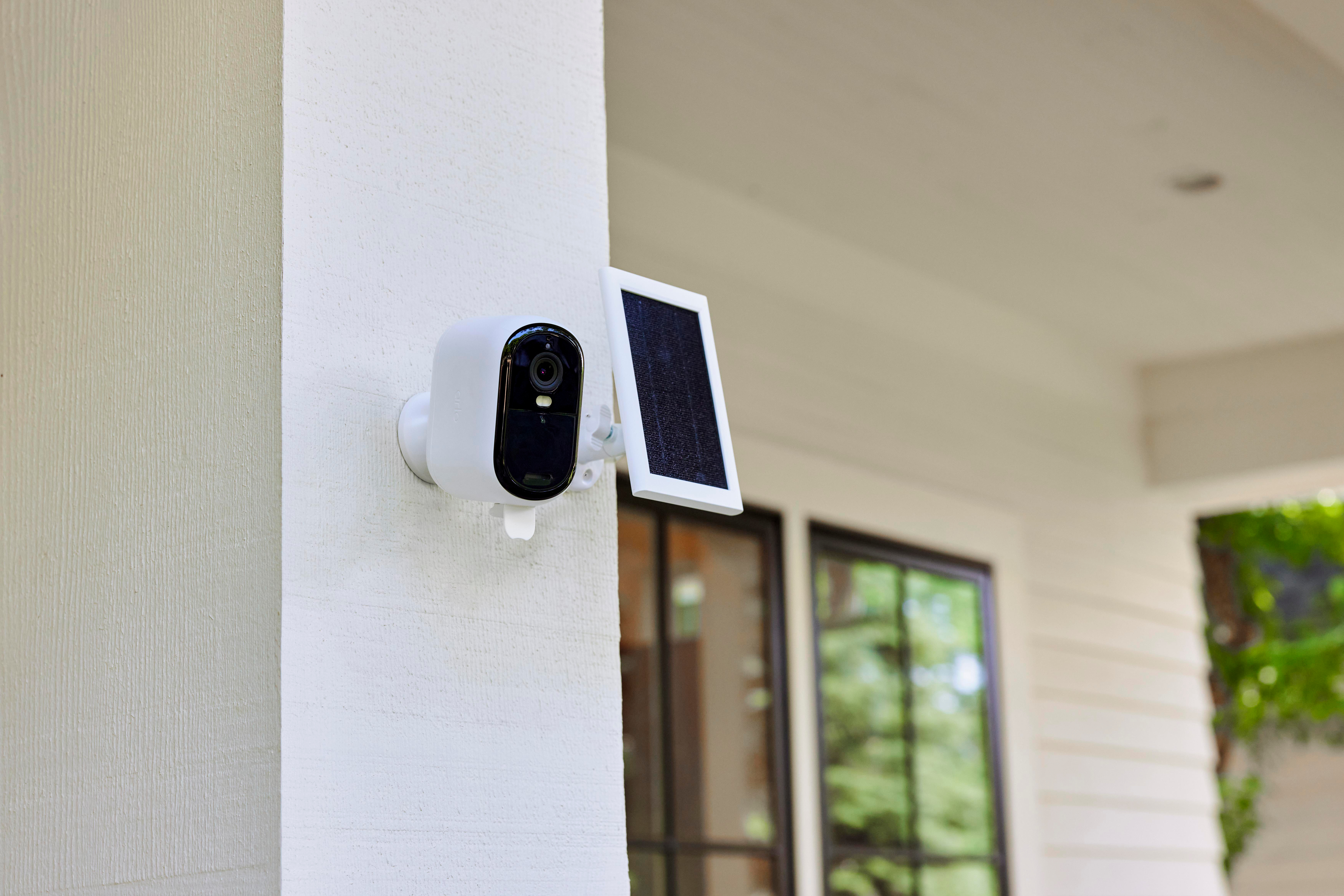 Weiße Überwachungskamera mit Solarpanel an der Wand montiert.