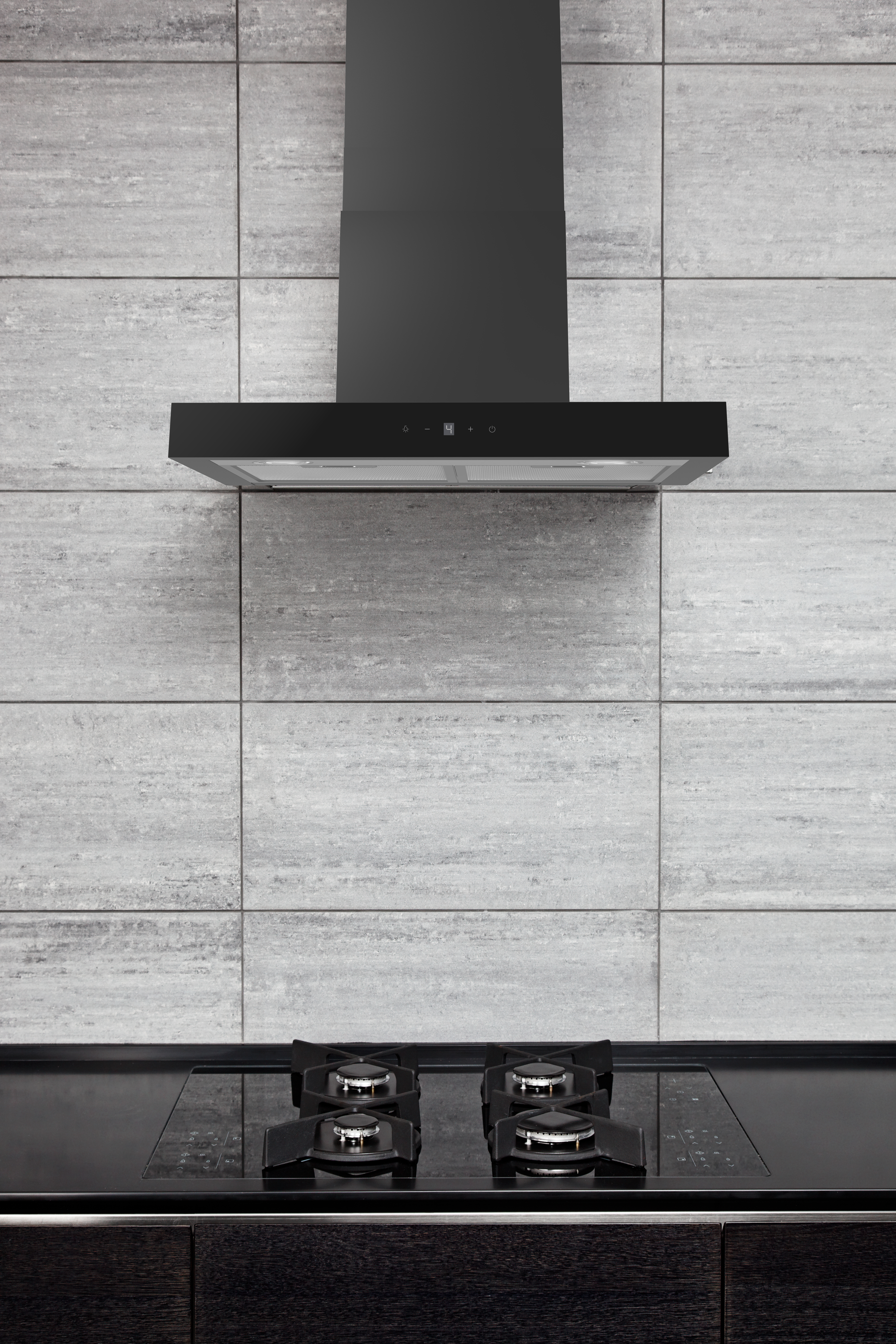 Black kitchen hood above a stove.  Grey tiled wall.  Dark wood cabinets.