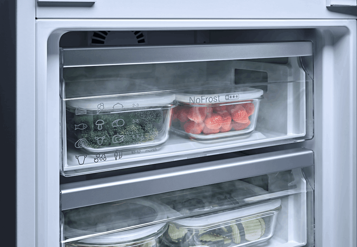 Dentro de un refrigerador: dos recipientes transparentes con comida, brócoli y fresas.