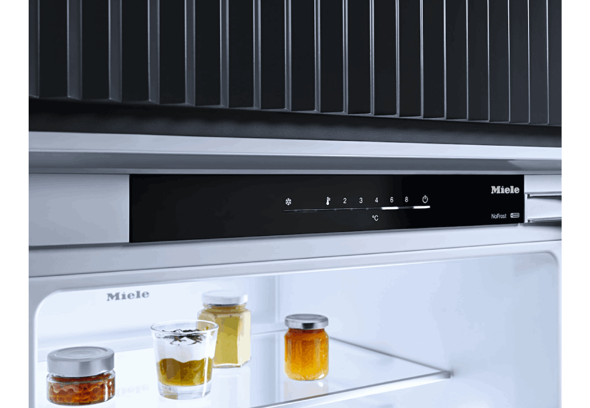 Interior de refrigerador con estantes de vidrio, tarros con comida y panel de control.