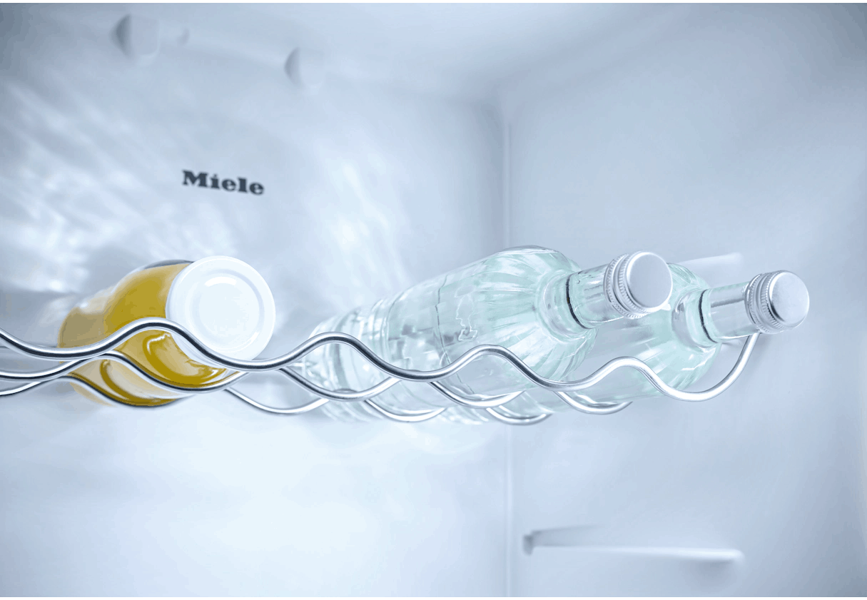Interior del refrigerador con botellas en una rejilla y un frasco.