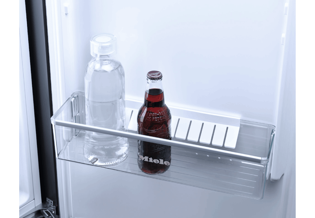 Estante de refrigerador con una botella de agua y una botella de refresco rojo.