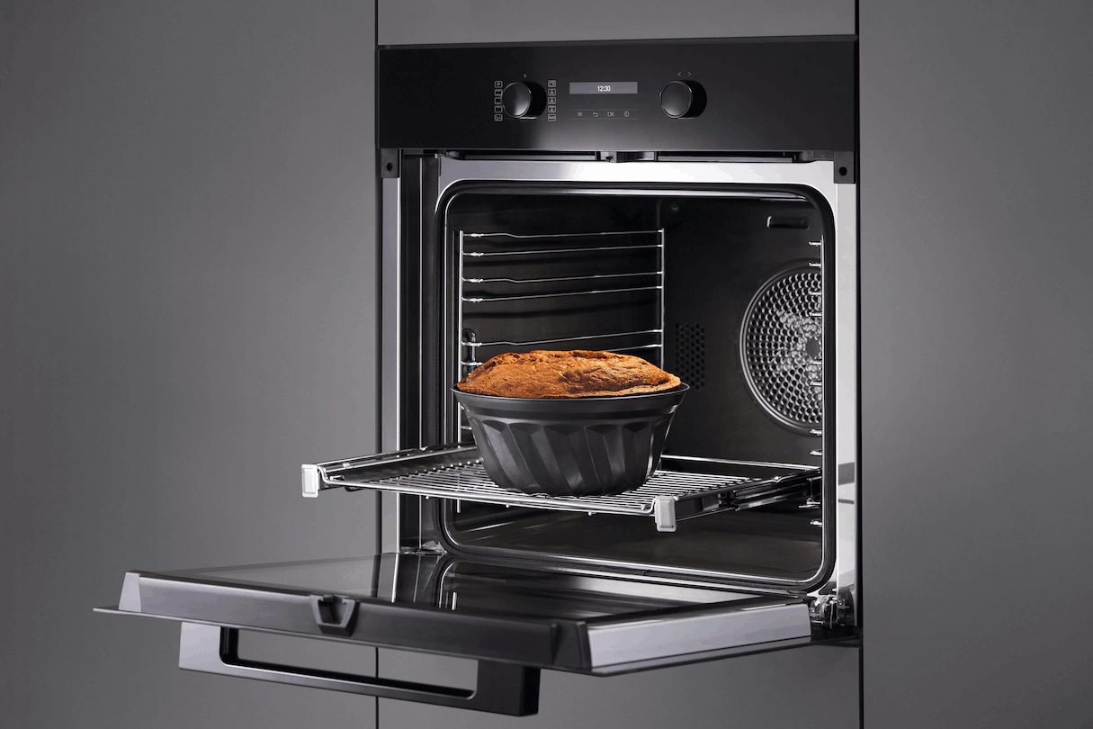 Un horno abierto con un pastel dentro sobre una rejilla.