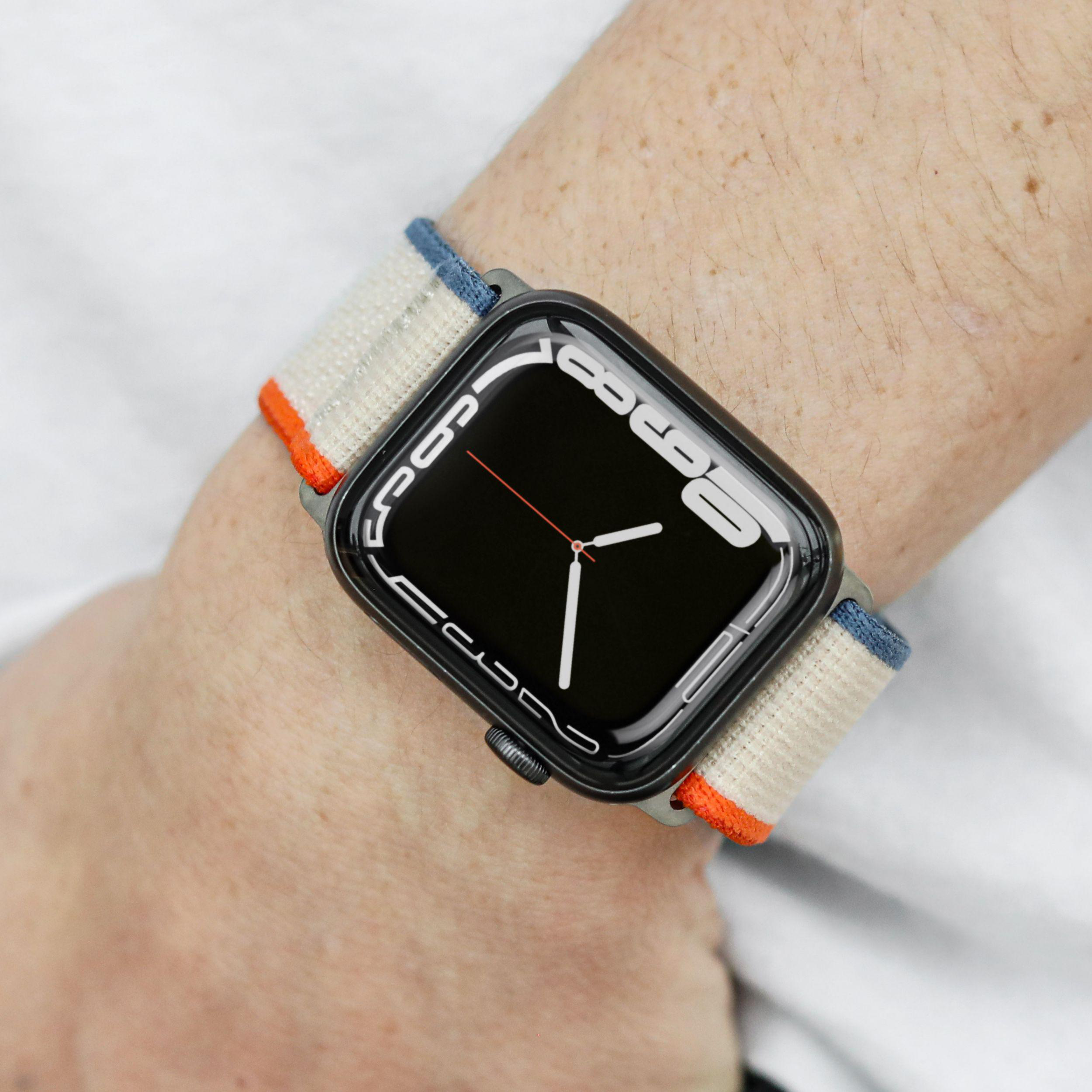 Handgelenk mit Apple Watch, beige-orangefarbenes Band.