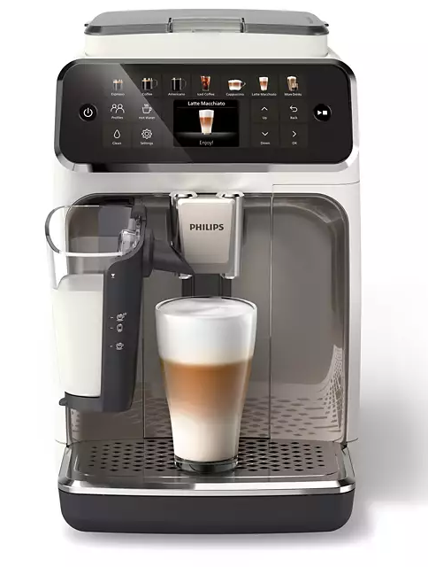 Fehér és ezüst kávéfőző, balra egy pohár latte macchiato-val és egy tejes tartállyal.