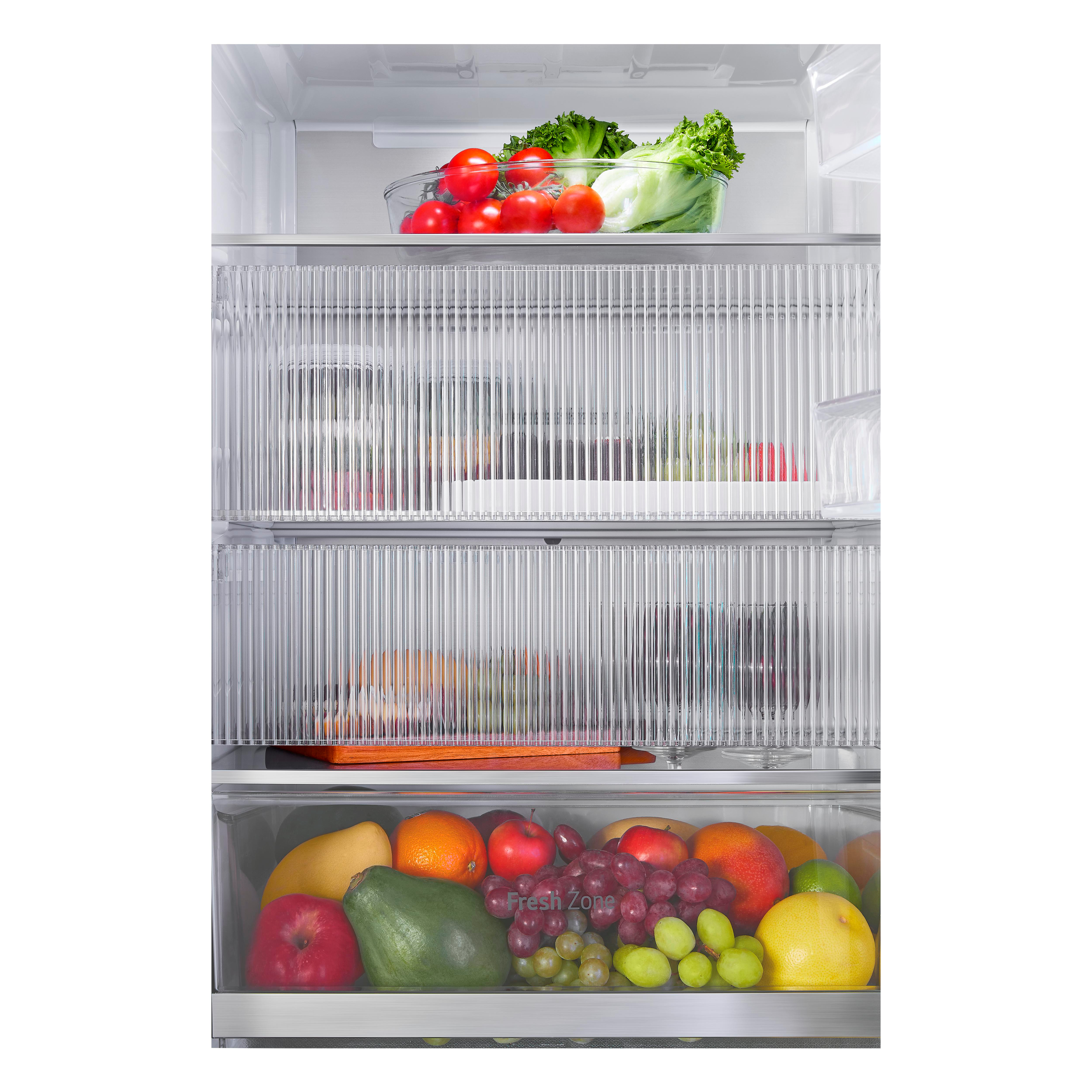 Im Inneren eines Kühlschranks mit Glasböden voller Obst, Gemüse und einer Schüssel Tomaten.