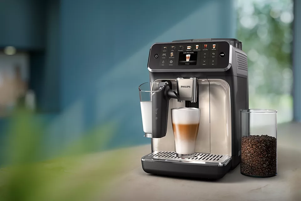 Kávéfőző egy pohár latte macchiatóval.