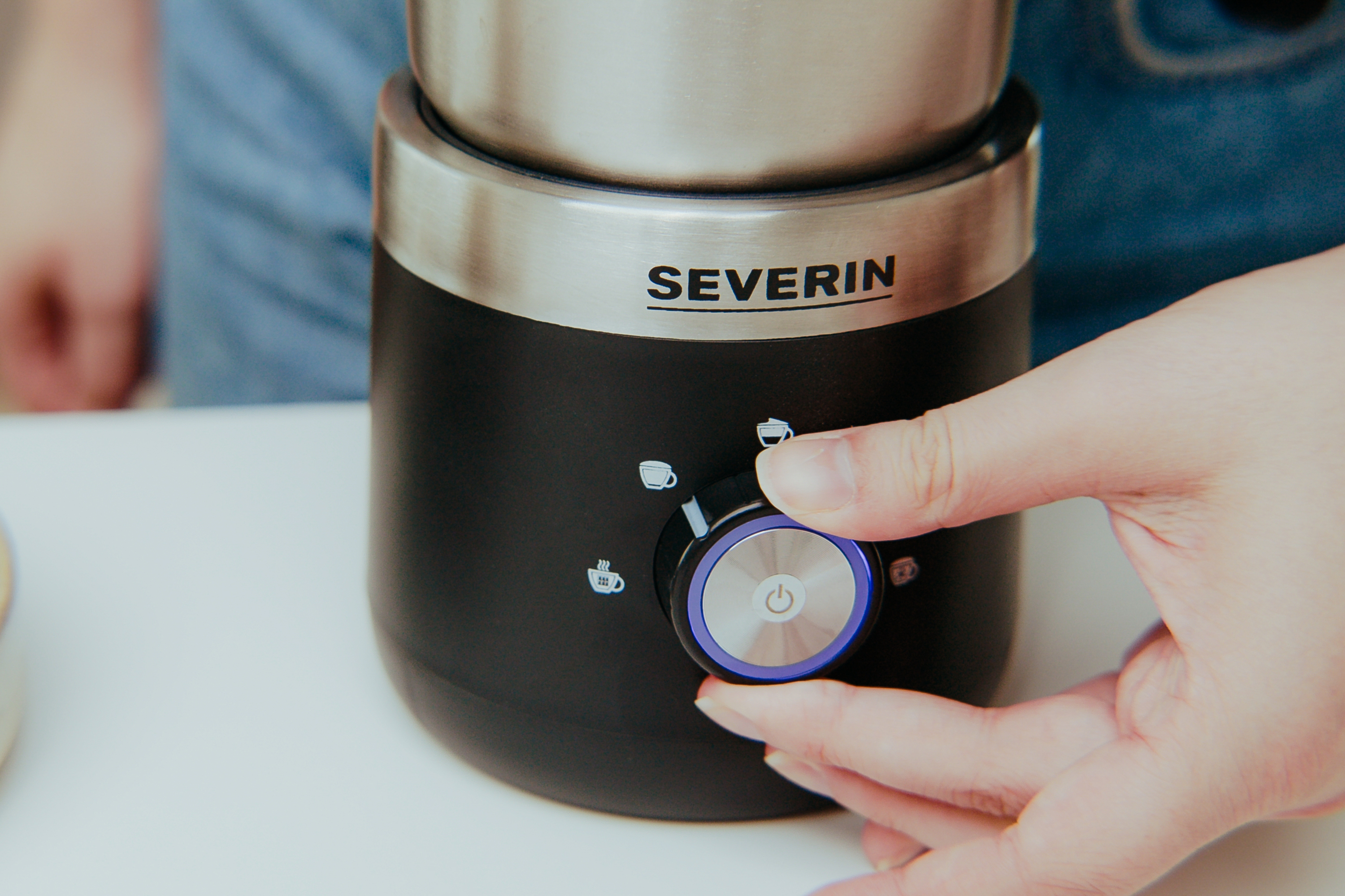 Person dreht einen Drehregler an einer schwarzen und silbernen Kaffeemühle. Severin ist vorne aufgedruckt.
