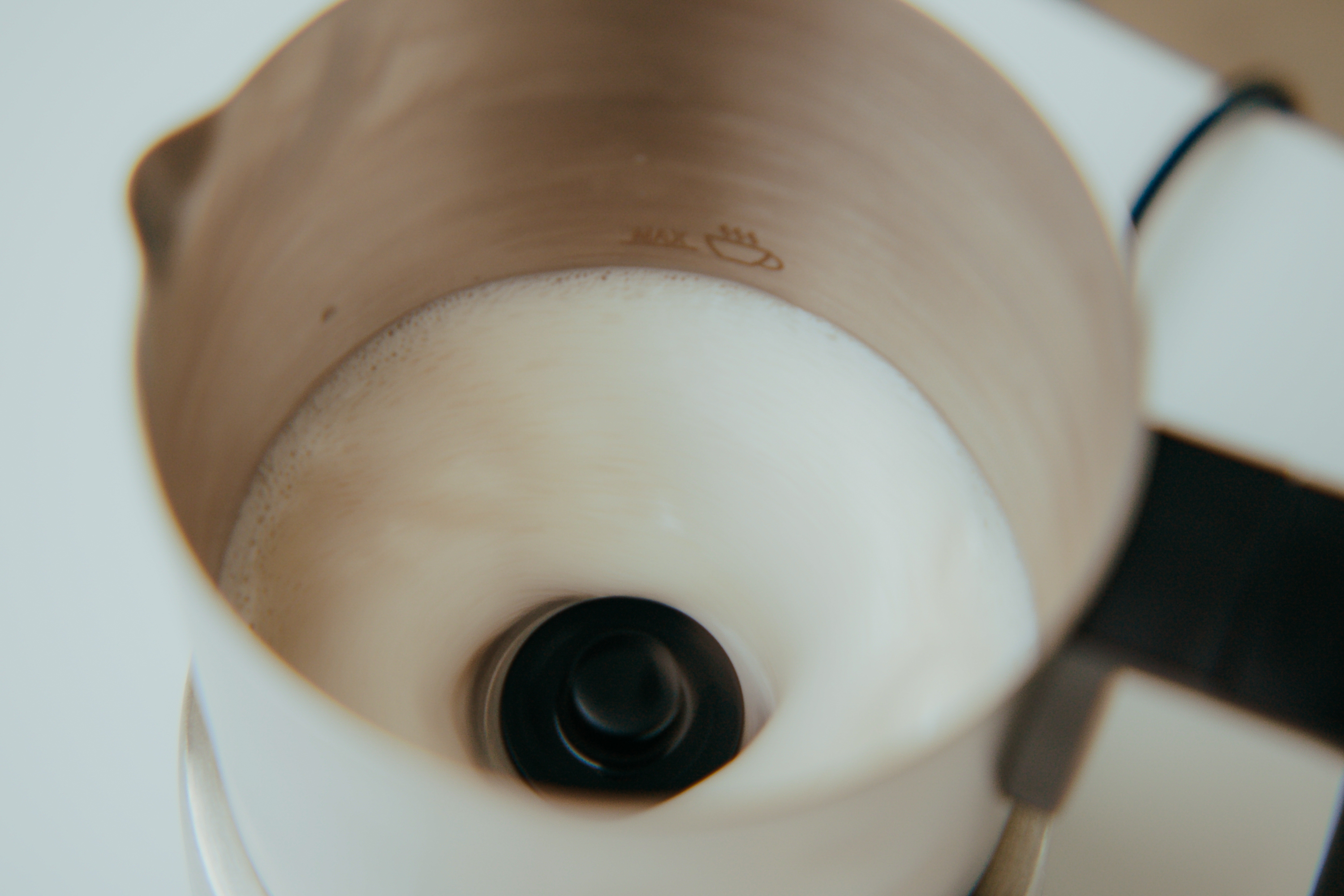 Nahaufnahme von schäumender Milch in einem Milchaufschäumer aus Metall.