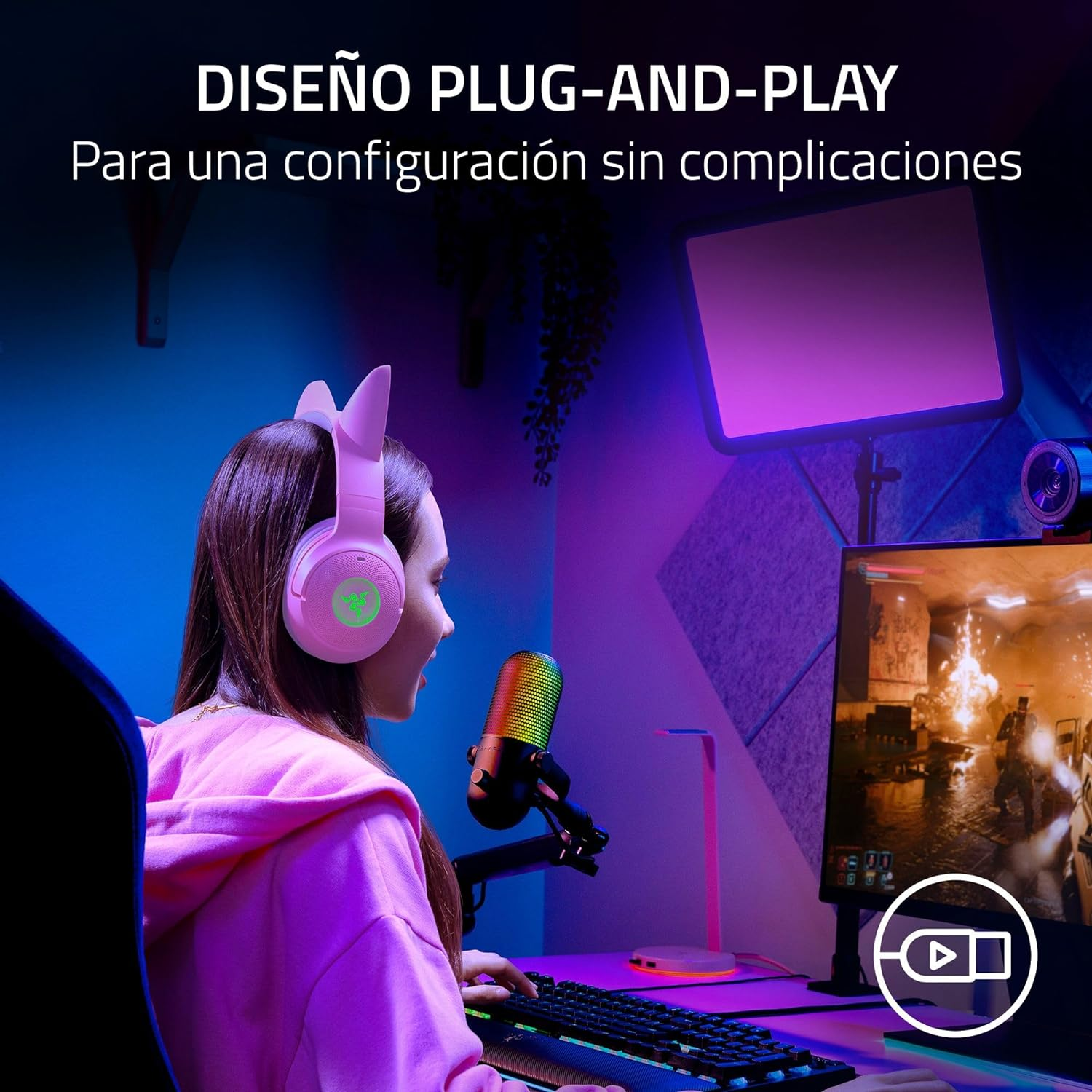 Jugador con auriculares rosas, micro y teclado. Monitor muestra escena de juego.