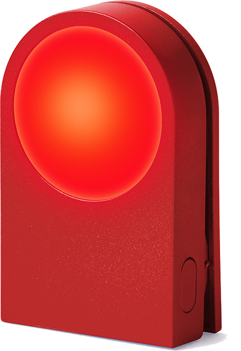 Czerwone, prostokątne urządzenie z świecącym czerwonym okręgiem pośrodku. Urządzenie ma zaokrąglone górne krawędzie.