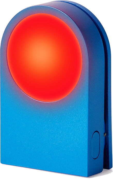 Niebieskie urządzenie z czerwonym, świecącym okręgiem. Ma zaokrągloną górę i małe wcięcie z boku.