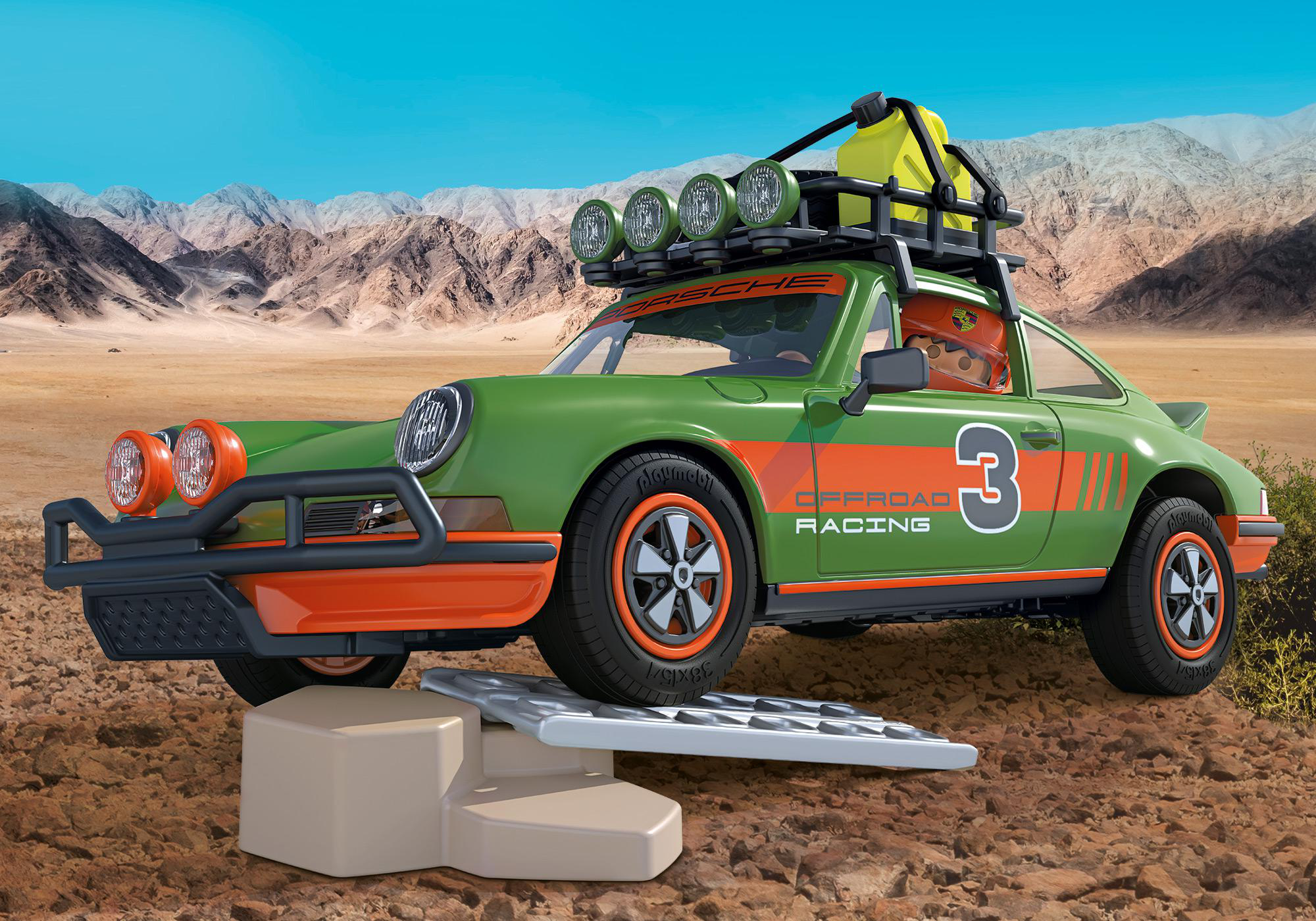 Grünes und oranges Spielzeugauto auf einer Rampe in einer Wüstenlandschaft. Das Auto hat eine 3.