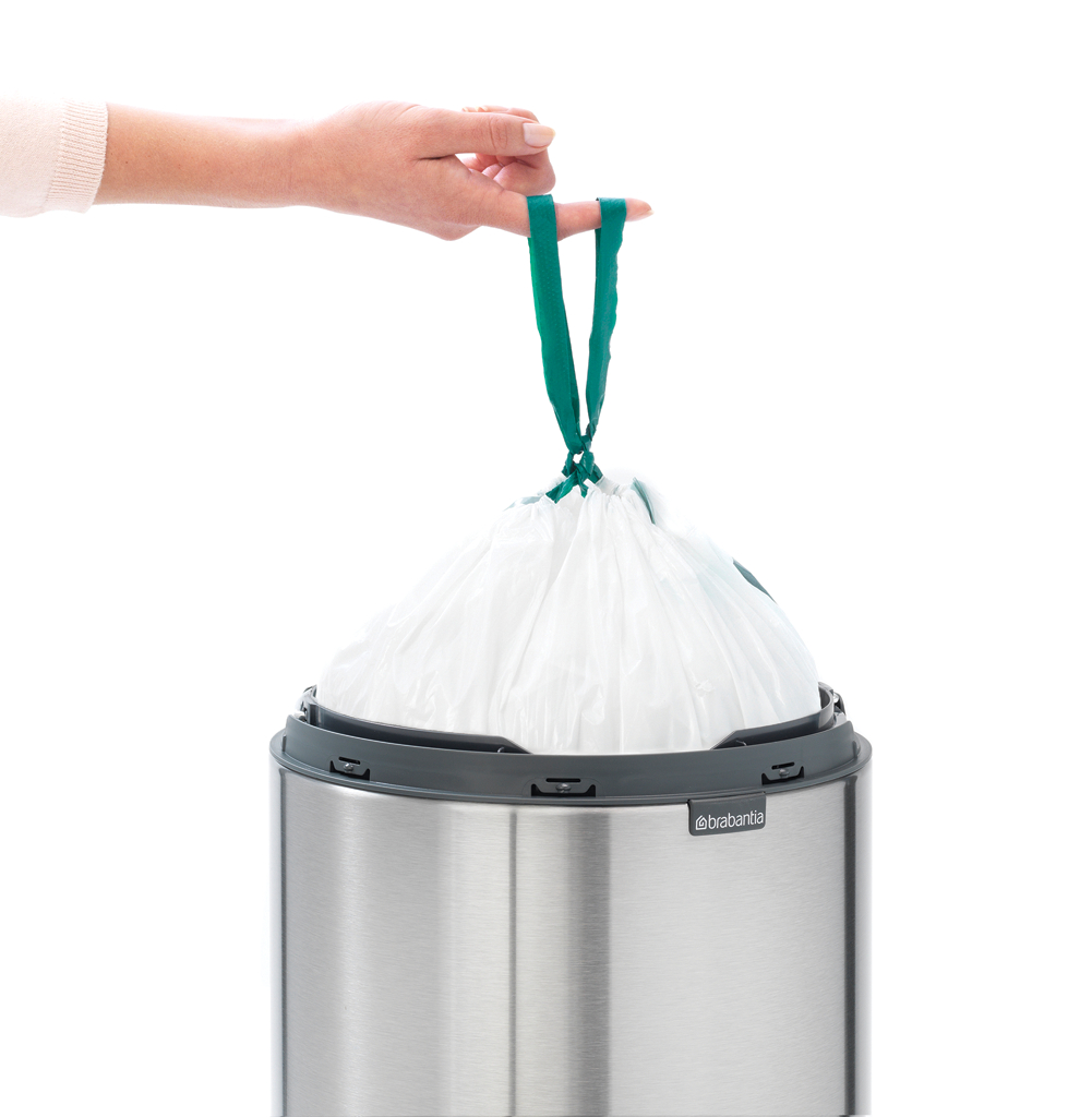 Hand hält weißen Müllsack. Grüne Bänder, Edelstahlbehälter. Weißer Hintergrund.
