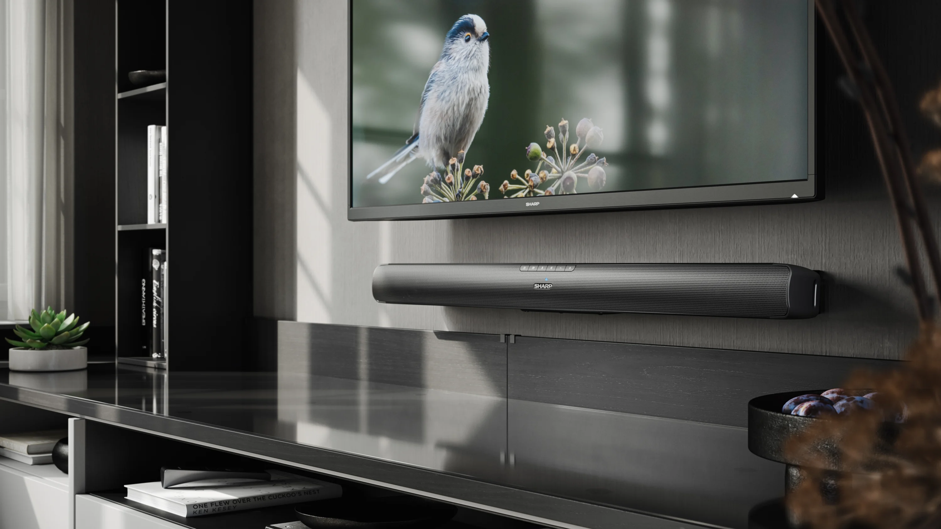Egy falra szerelt TV és egy soundbar. A TV képet jelenít meg. A soundbar a TV alatt van.