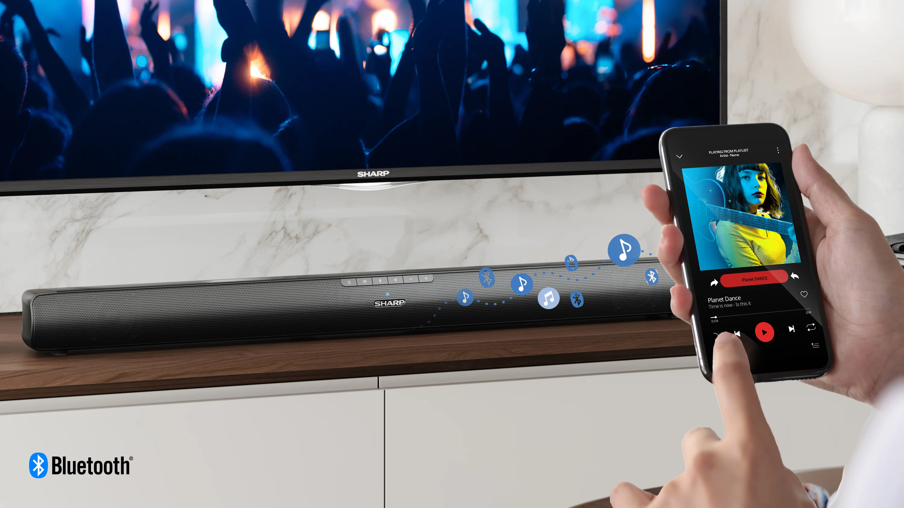 Személy telefonnal vezérli a TV előtt lévő soundbaron lejátszott zenét.