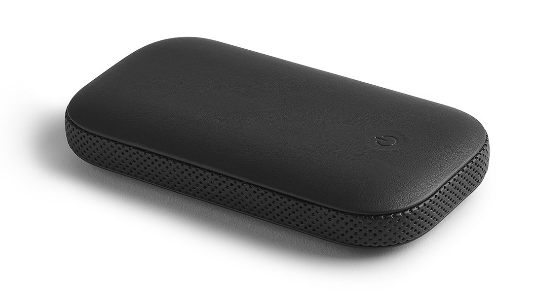 Czarne, prostokątne urządzenie z przyciskiem zasilania na białej powierzchni.