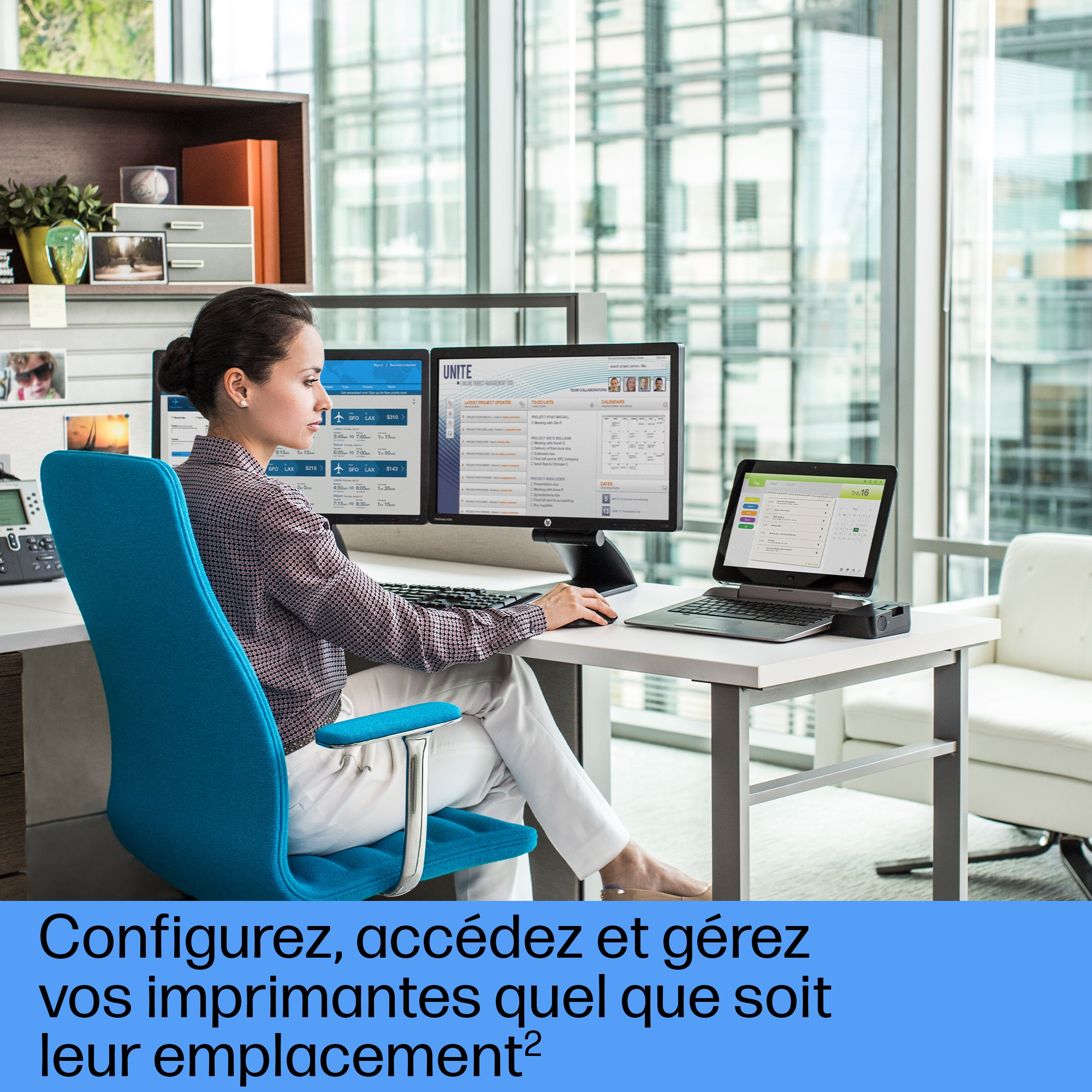 Femme assise sur une chaise bleue au bureau, travaillant sur des écrans.