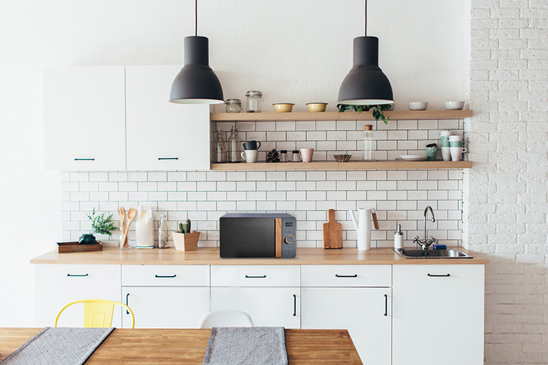 Un forno a microonde nero e di legno su un piano di lavoro della cucina.