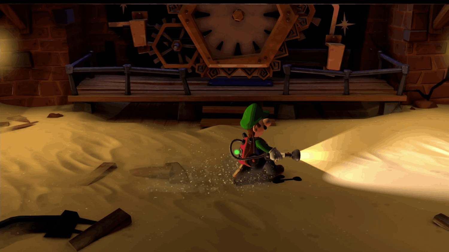 Luigi corriendo por una habitación arenosa, sosteniendo una linterna, en una escena de videojuego.