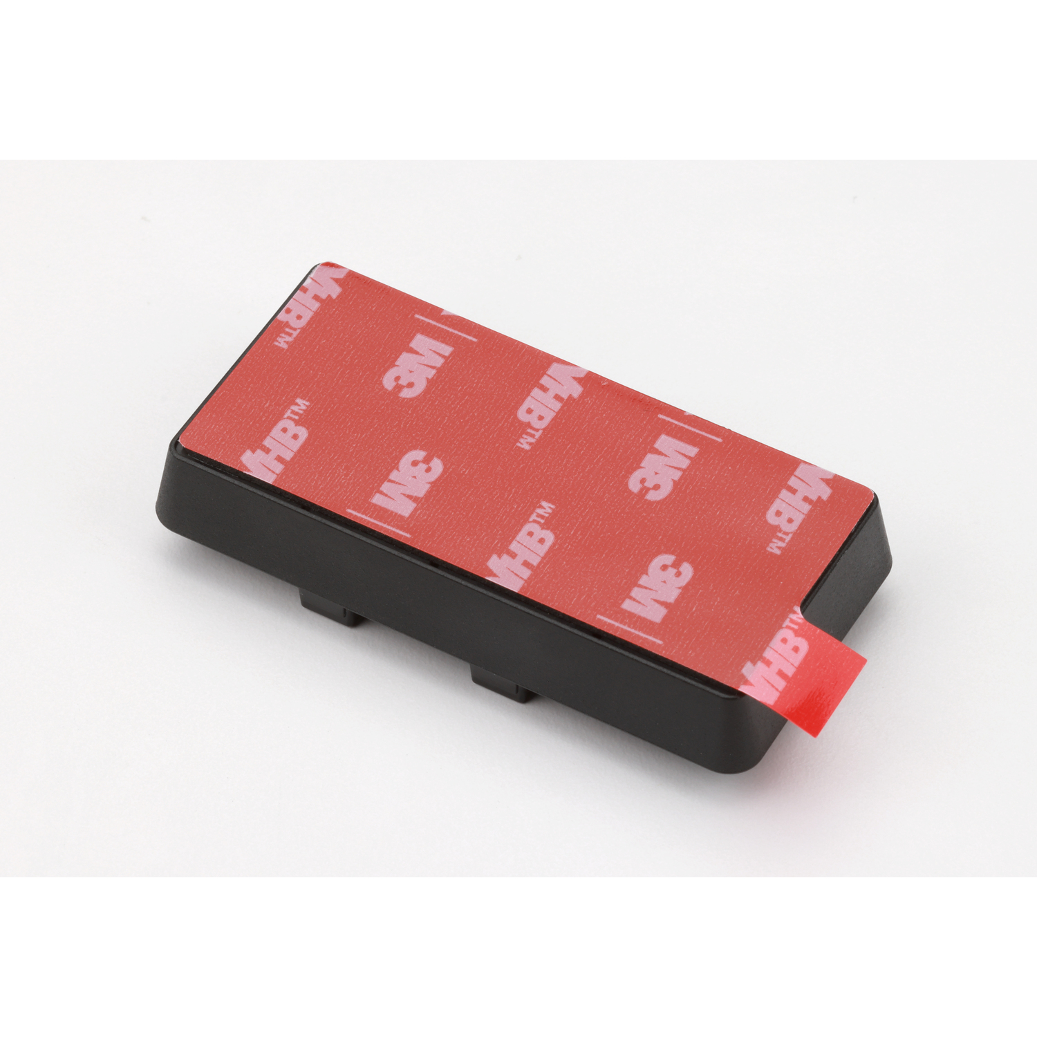 Black rectangular object with red adhesive tape. The tape has '3M VHB' printed on it. 