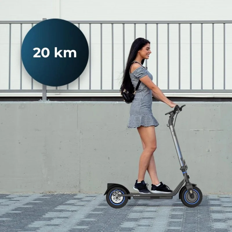 Kobieta jedzie hulajnogą elektryczną po chodniku, niebieskie koło wskazuje zasięg 20 km.