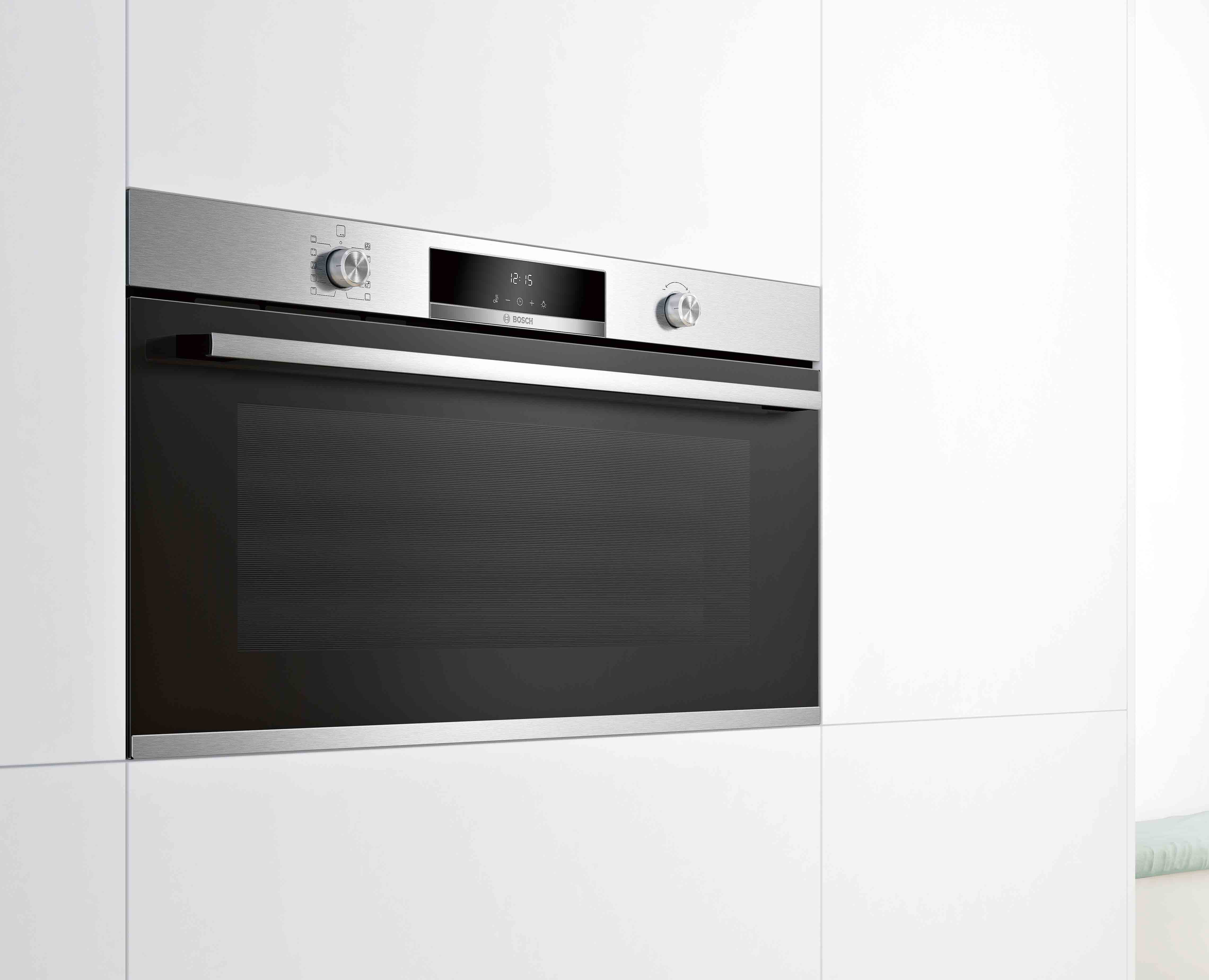 Horno empotrado en una cocina blanca. Acabado de acero inoxidable, panel de control y puerta de vidrio visibles.